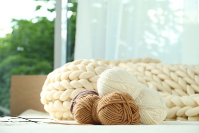 Photo of Skeins of yarn and knitting needles on soft blanket