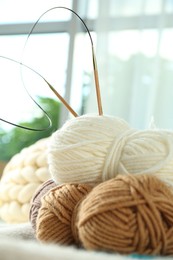 Photo of Skeins of yarn and knitting needles on soft blanket, closeup