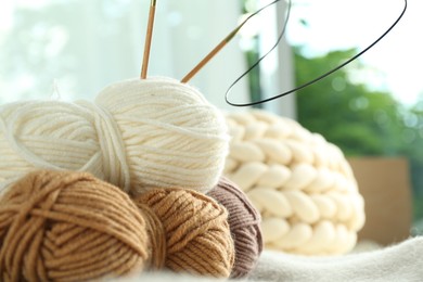 Photo of Skeins of yarn and knitting needles on soft blanket, closeup