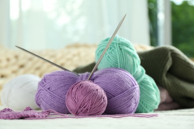 Photo of Bright yarns, pattern sample and knitting needles on soft blanket, closeup