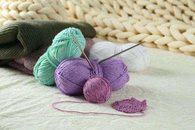 Photo of Bright yarns, pattern sample and knitting needles on soft blanket