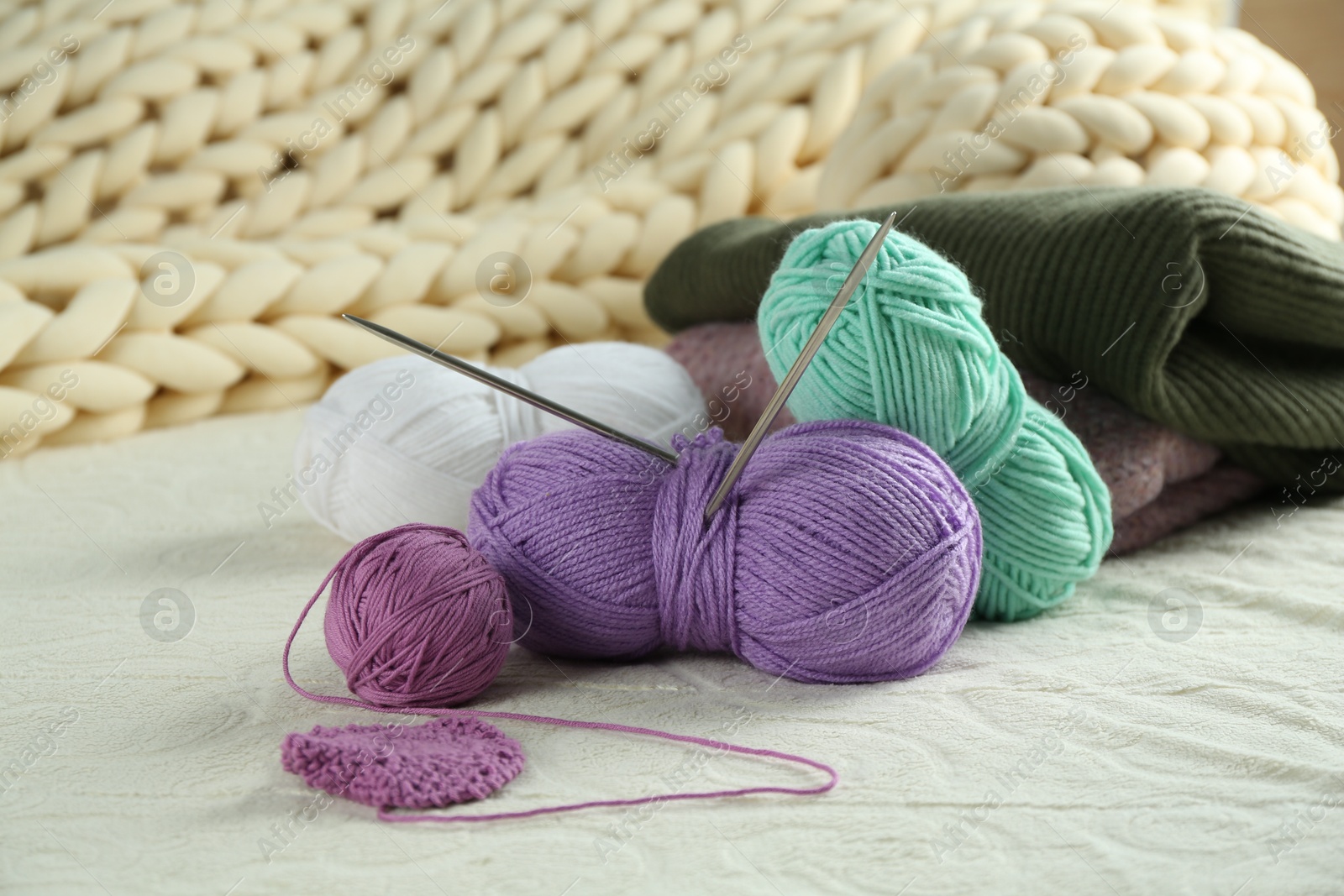 Photo of Bright yarns, pattern sample and knitting needles on soft blanket