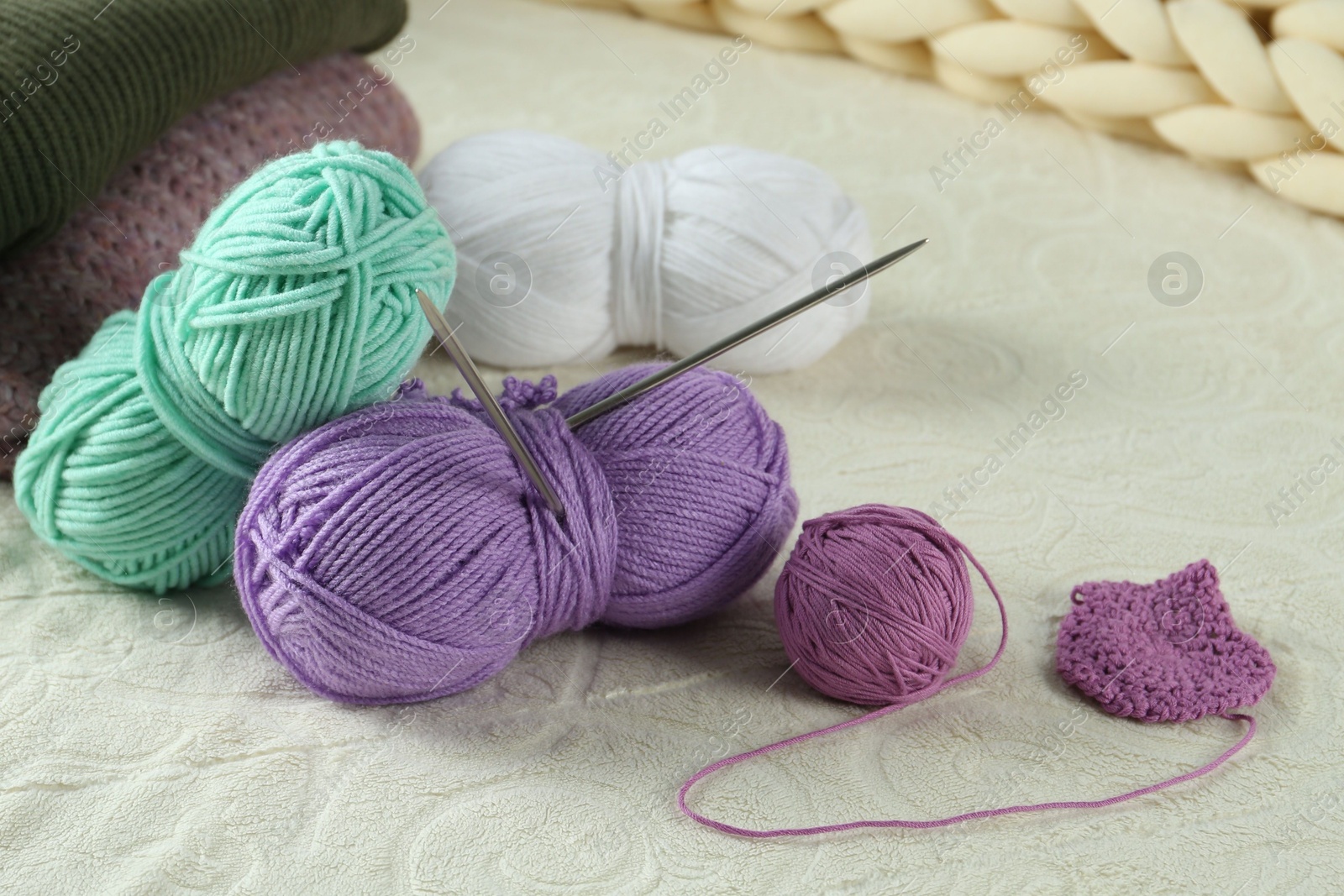 Photo of Bright yarns, pattern sample and knitting needles on soft blanket