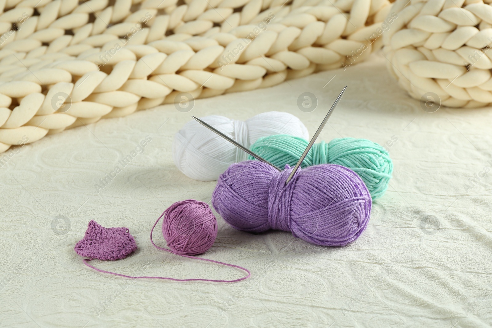 Photo of Bright yarns, pattern sample and knitting needles on soft blanket