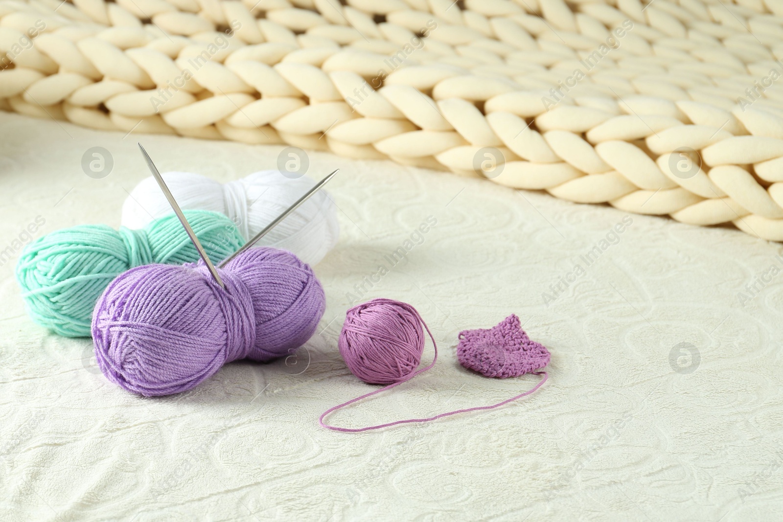 Photo of Bright yarns, pattern sample and knitting needles on soft blanket