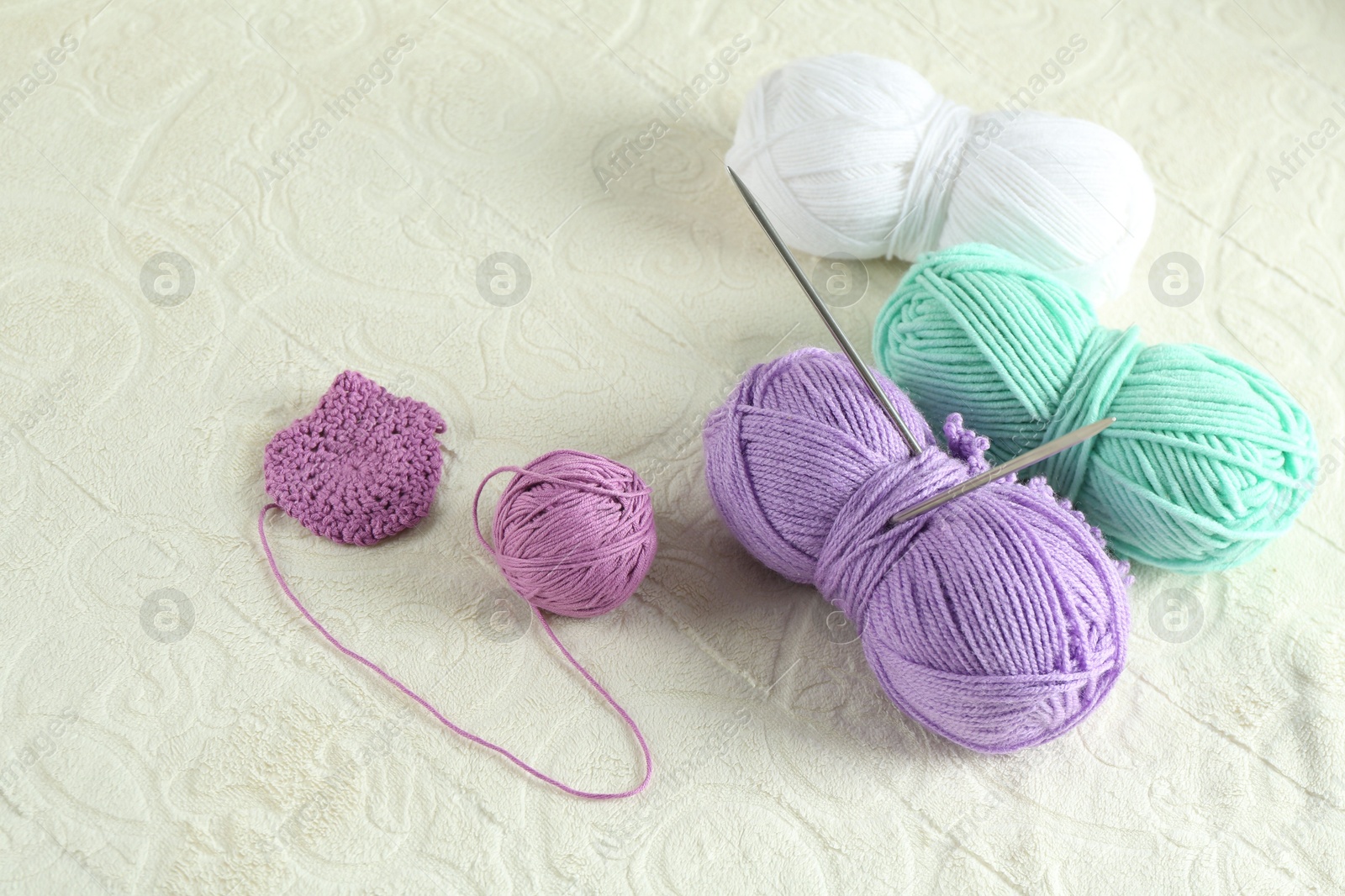 Photo of Bright yarns and knitting needles on soft blanket, above view