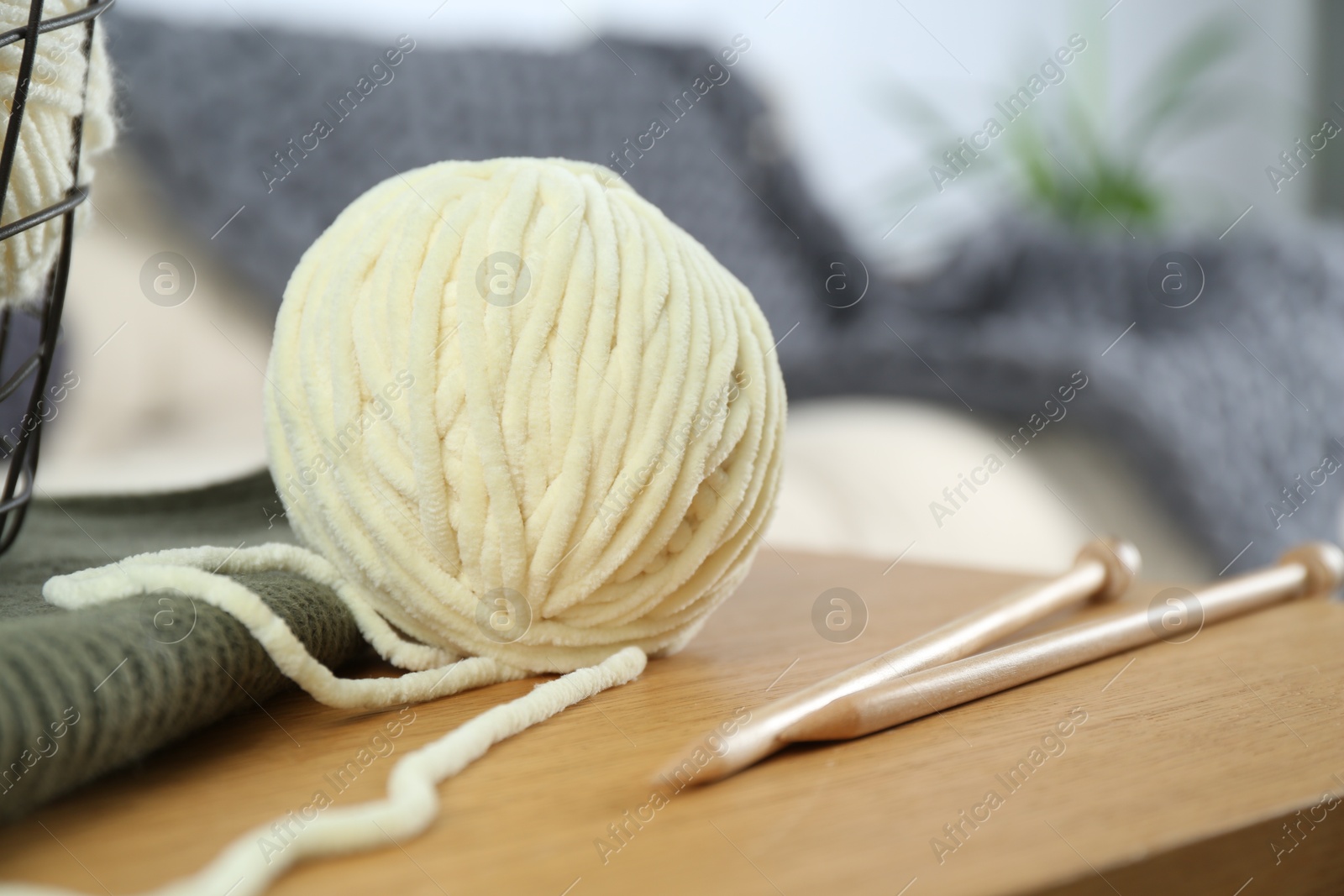 Photo of Ball of yarn and knitting needles on wooden table indoors, closeup