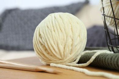 Ball of yarn and knitting needles on wooden table indoors, closeup