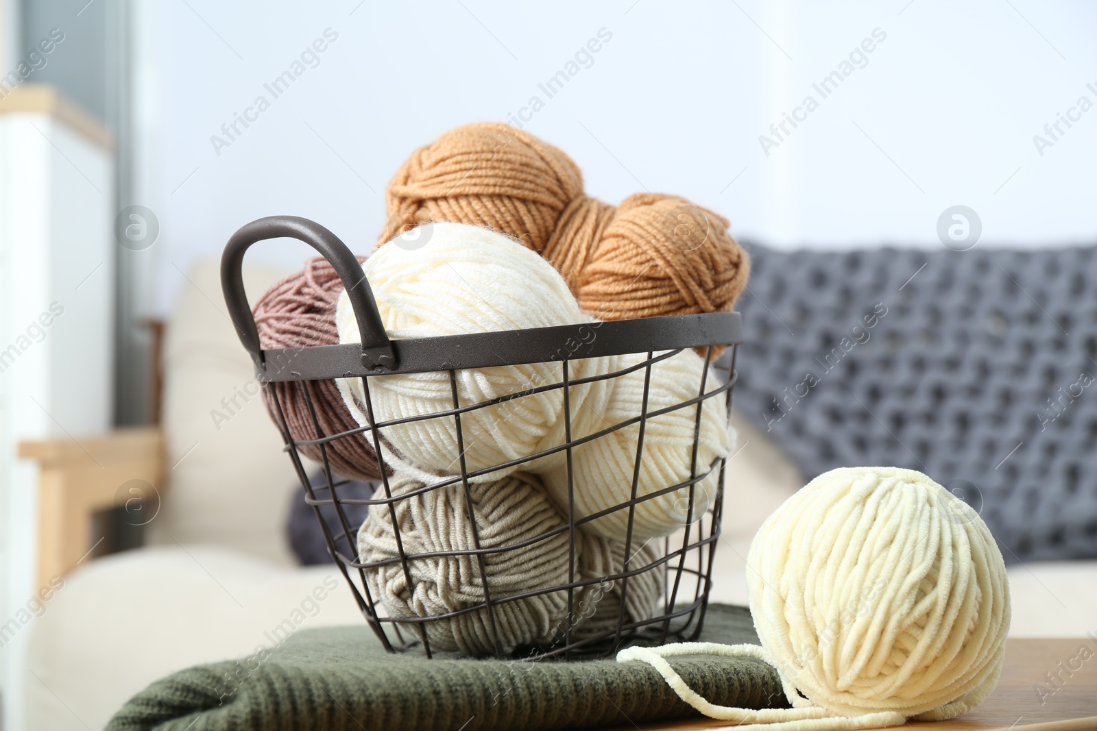 Photo of Basket with yarns and sweater on table indoors