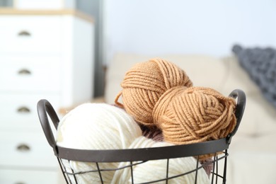 Photo of Colorful yarns in metal basket indoors, closeup