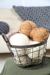 Photo of Basket with yarns and sweater on table indoors