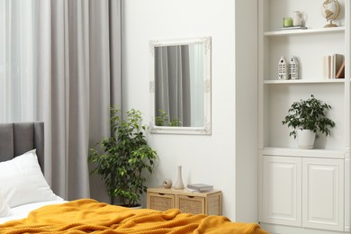 Photo of Mirror on white wall in bedroom. Interior design