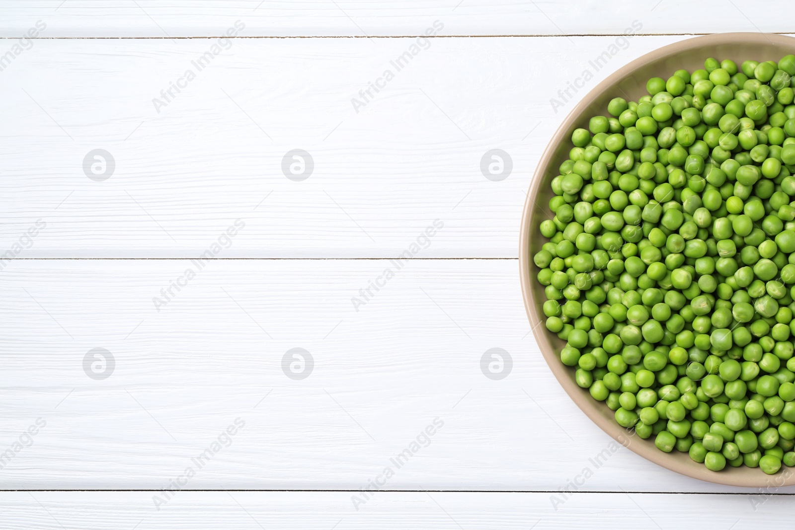 Photo of Fresh green peas on white wooden table, top view. Space for text