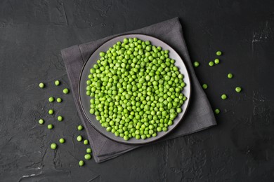 Photo of Fresh green peas in plate on black table, flat lay