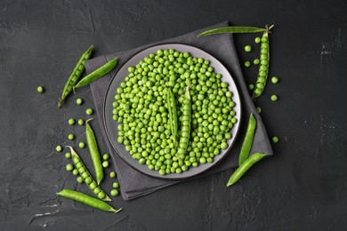 Photo of Fresh green peas and pods on black table, flat lay