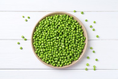 Photo of Fresh green peas in plate on white wooden table, top view