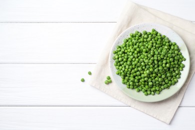 Photo of Fresh green peas in plate on white wooden table, top view. Space for text