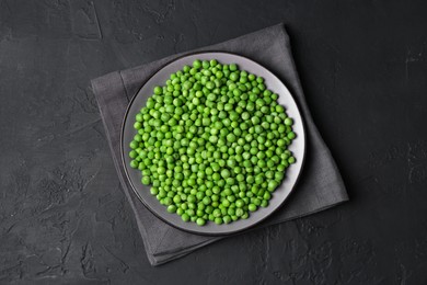 Fresh green peas in plate on black table, top view