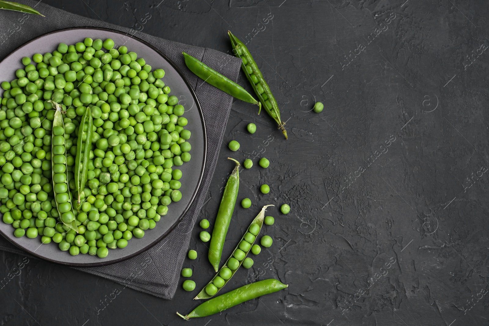 Photo of Fresh green peas and pods on black table, flat lay. Space for text