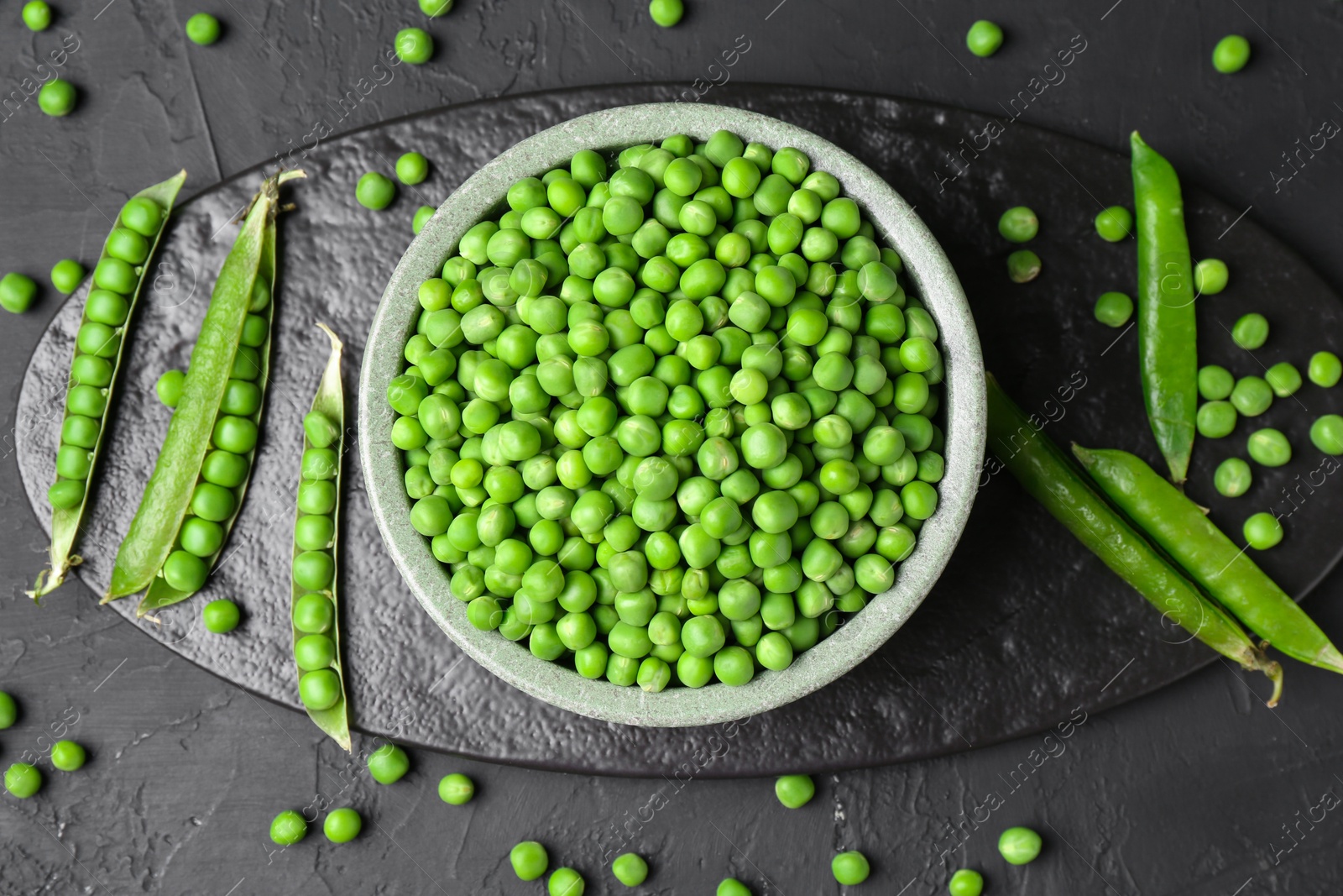 Photo of Fresh green peas and pods on black table, flat lay