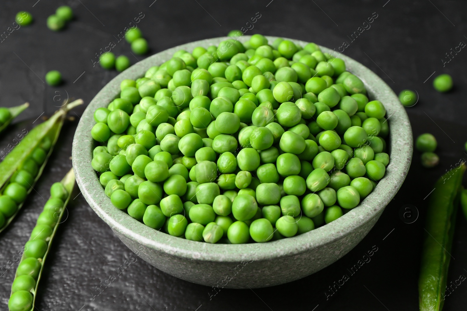 Photo of Fresh green peas and pods on black table