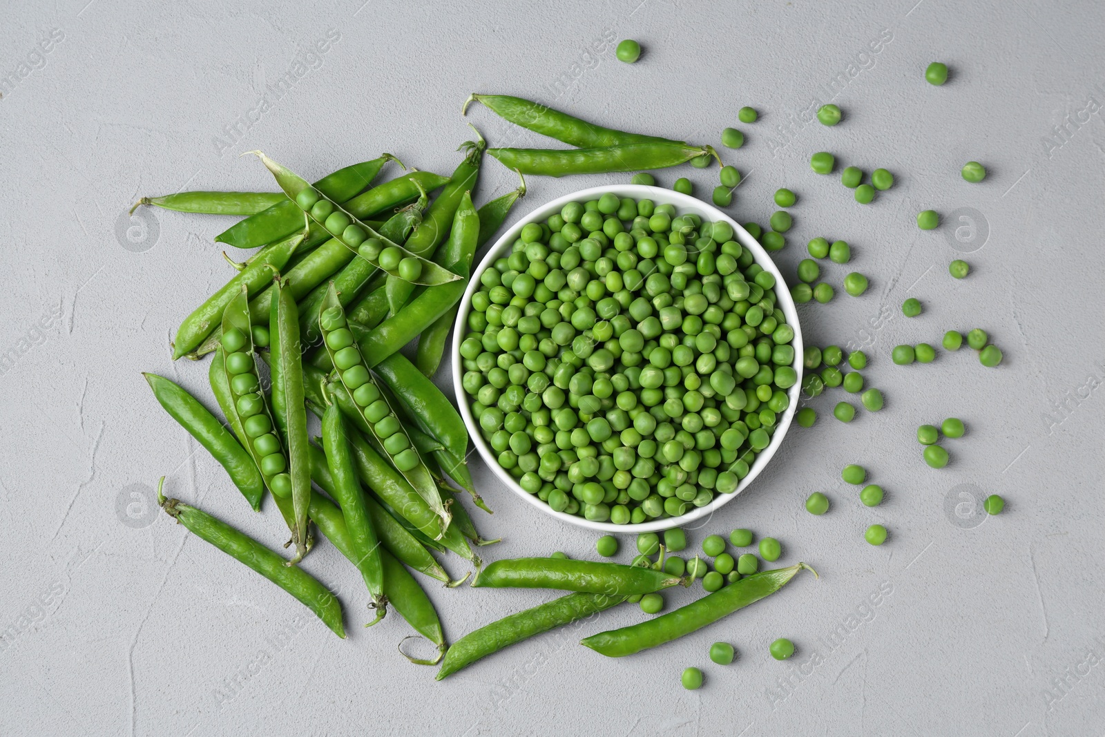 Photo of Fresh green peas and pods on grey table, flat lay