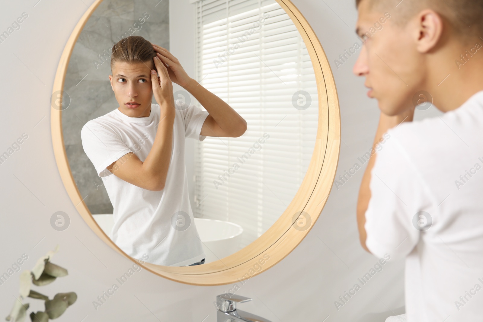 Photo of Handsome man looking at mirror in bathroom