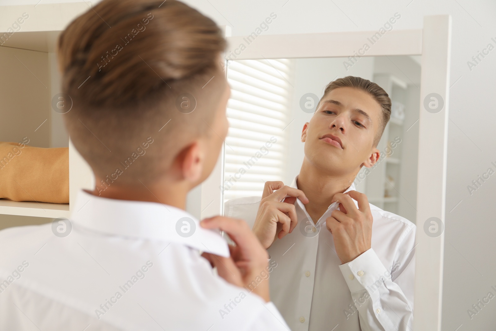 Photo of Handsome man in shirt near mirror indoors