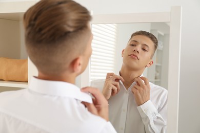 Handsome man in shirt near mirror indoors