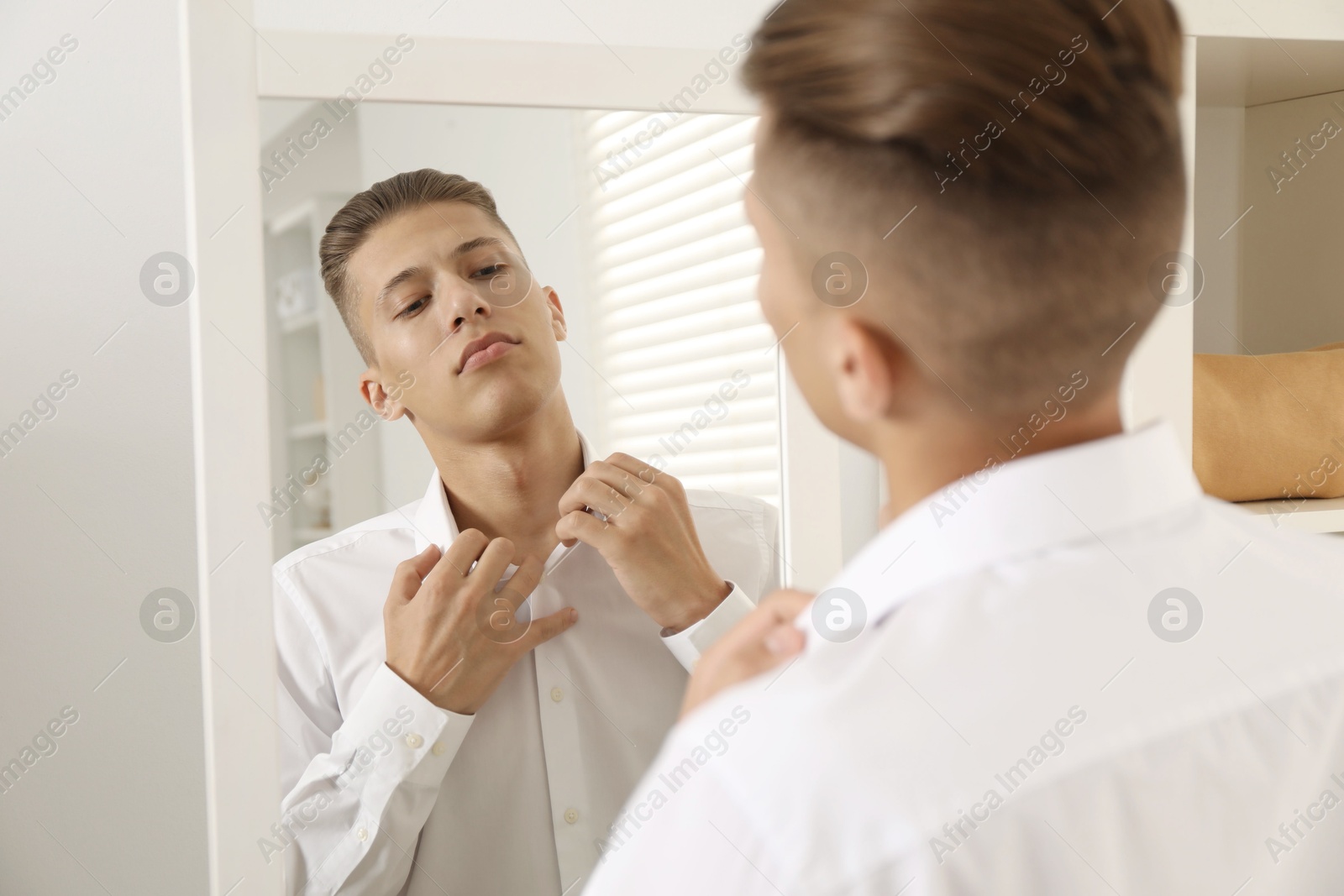 Photo of Handsome man in shirt near mirror indoors