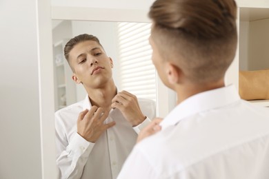 Handsome man in shirt near mirror indoors