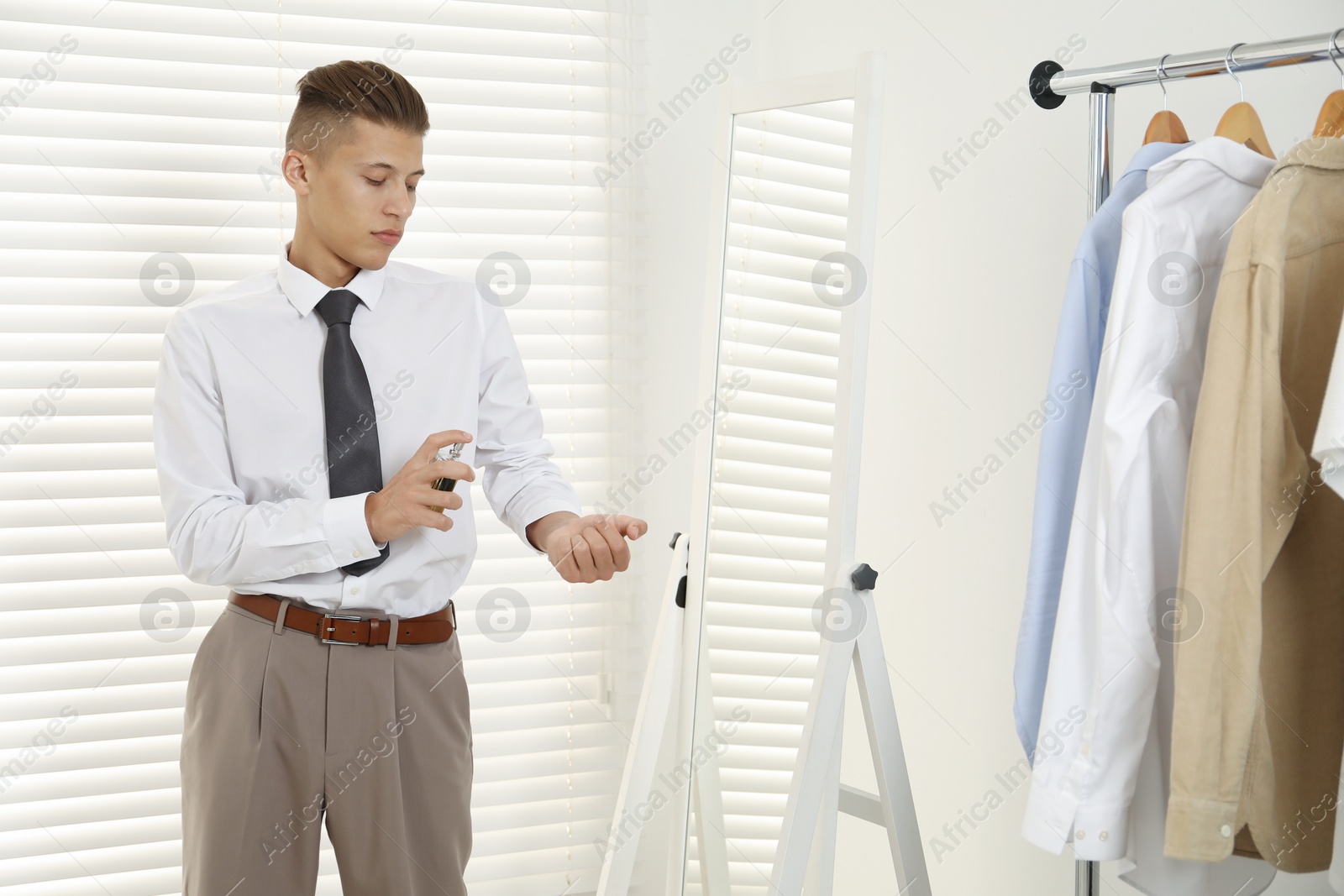 Photo of Man spraying luxury perfume near mirror indoors