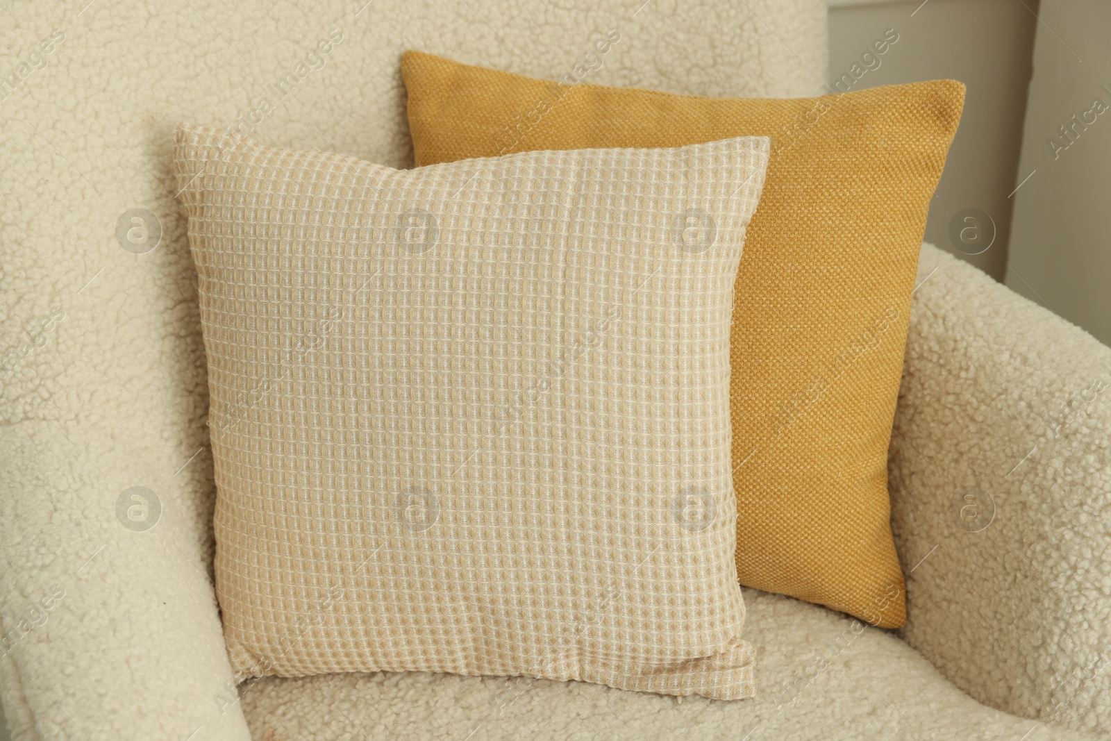 Photo of Two soft pillows on light armchair indoors