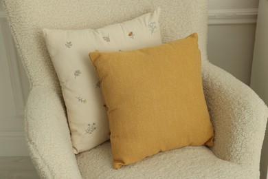 Photo of Two soft pillows on light armchair indoors