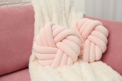 Photo of Decorative pillows and fluffy blanket on pink sofa indoors