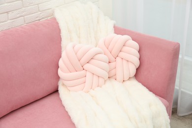 Photo of Decorative pillows and fluffy blanket on pink sofa indoors