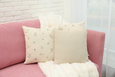 Photo of Decorative pillows and fluffy blanket on pink sofa indoors