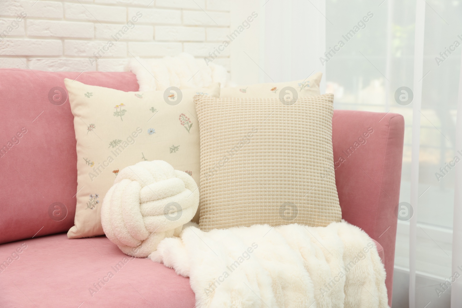 Photo of Decorative pillows and fluffy blanket on pink sofa indoors