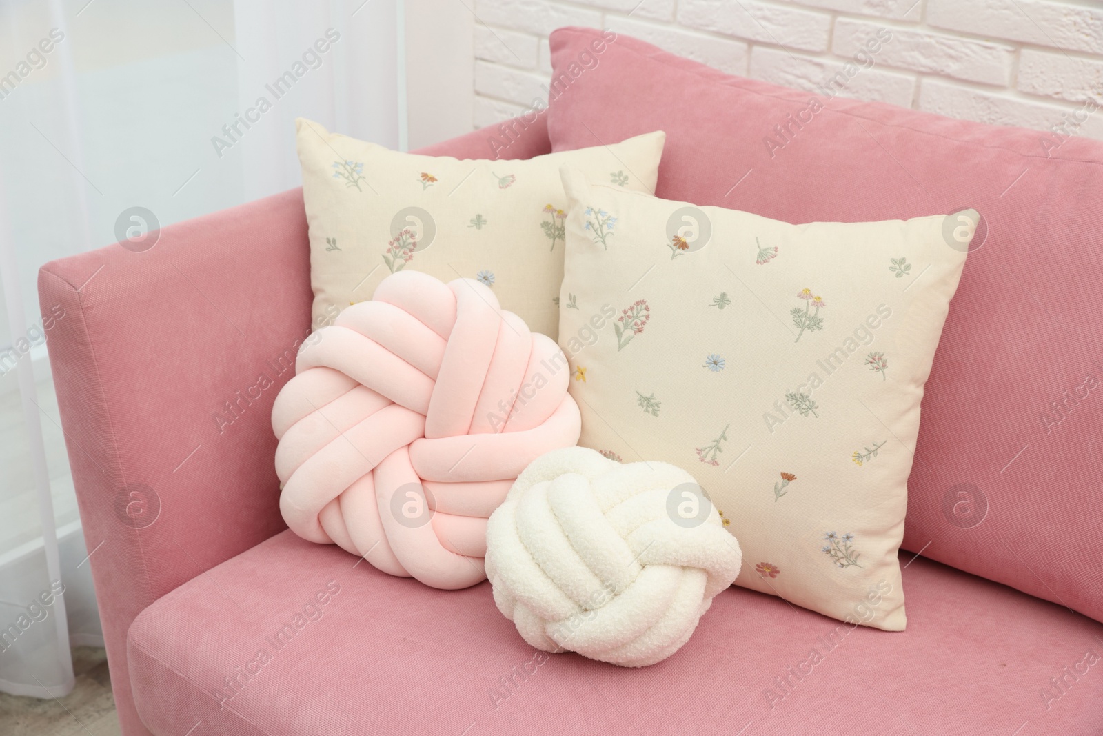 Photo of Soft decorative pillows on pink sofa indoors