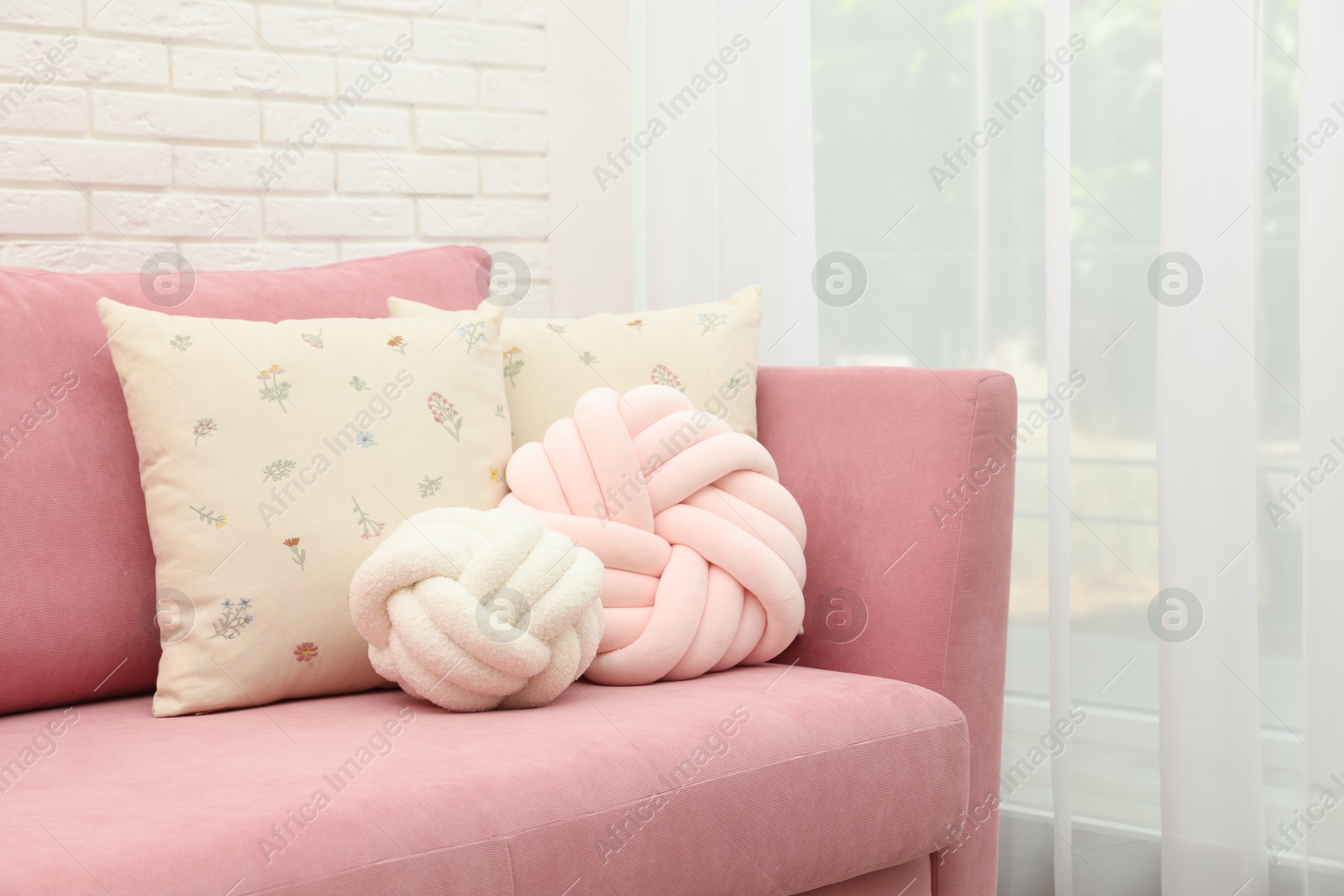 Photo of Soft decorative pillows on pink sofa indoors