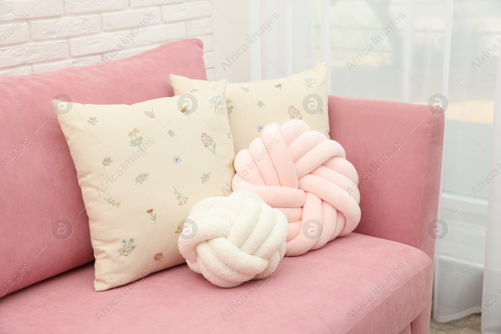 Photo of Soft decorative pillows on pink sofa indoors