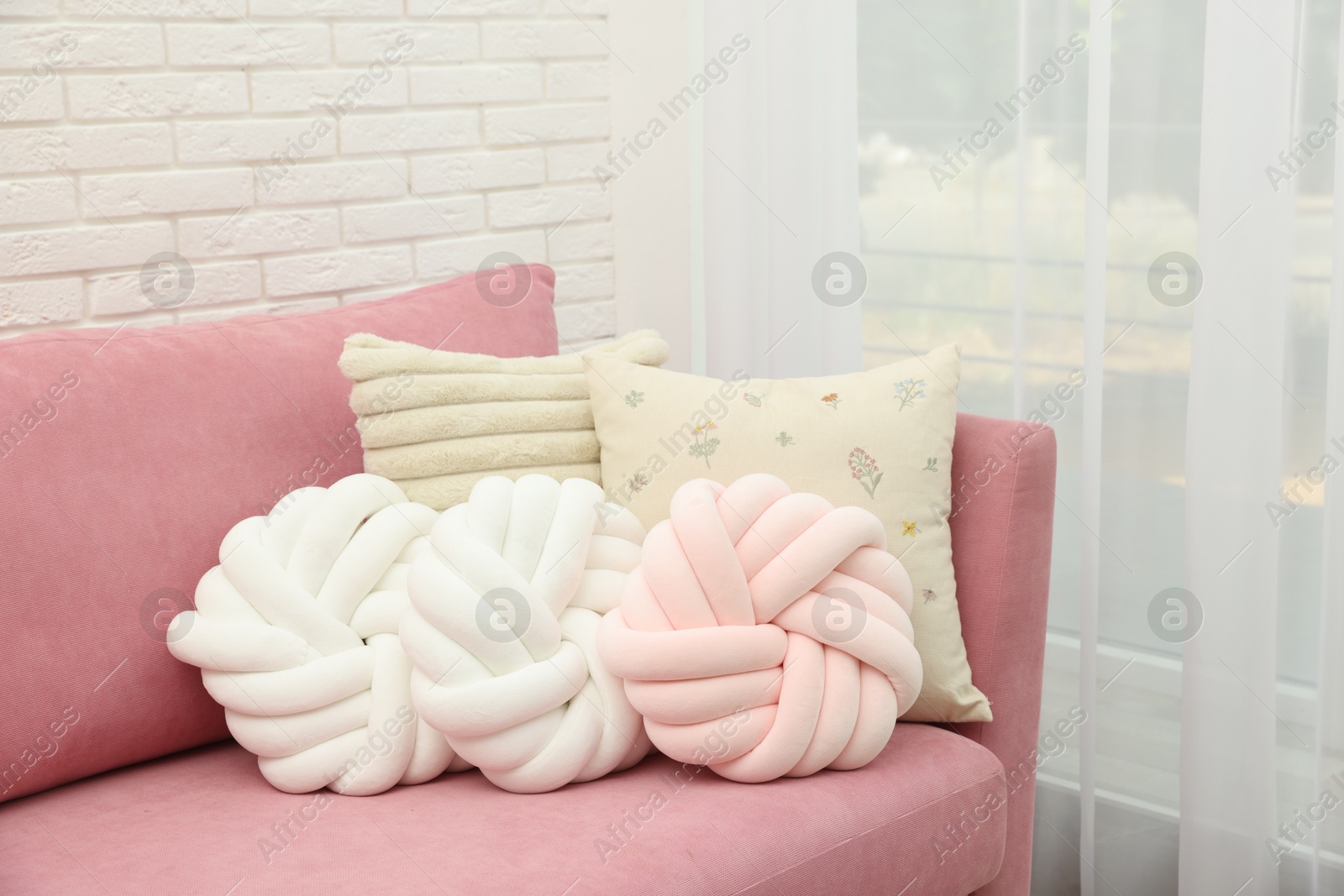 Photo of Soft decorative pillows on pink sofa indoors