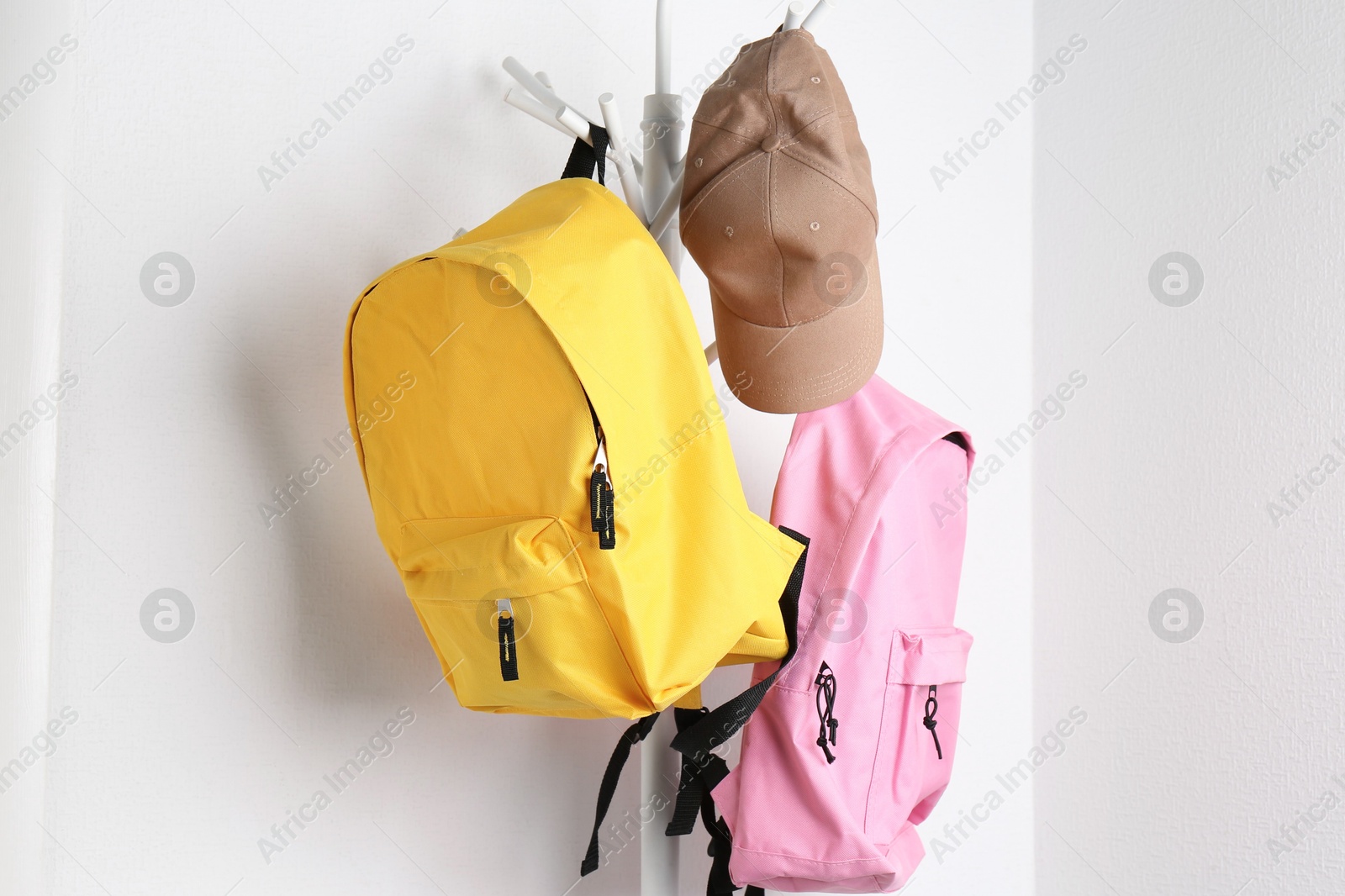 Photo of Bright backpacks and cap hanging on white wall