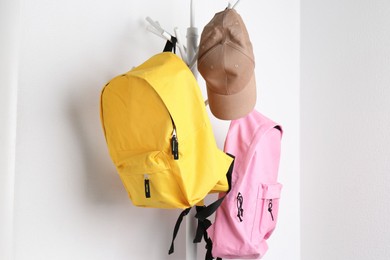 Photo of Bright backpacks and cap hanging on white wall