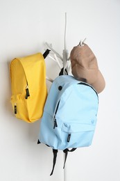 Photo of Bright backpacks and cap hanging on white wall