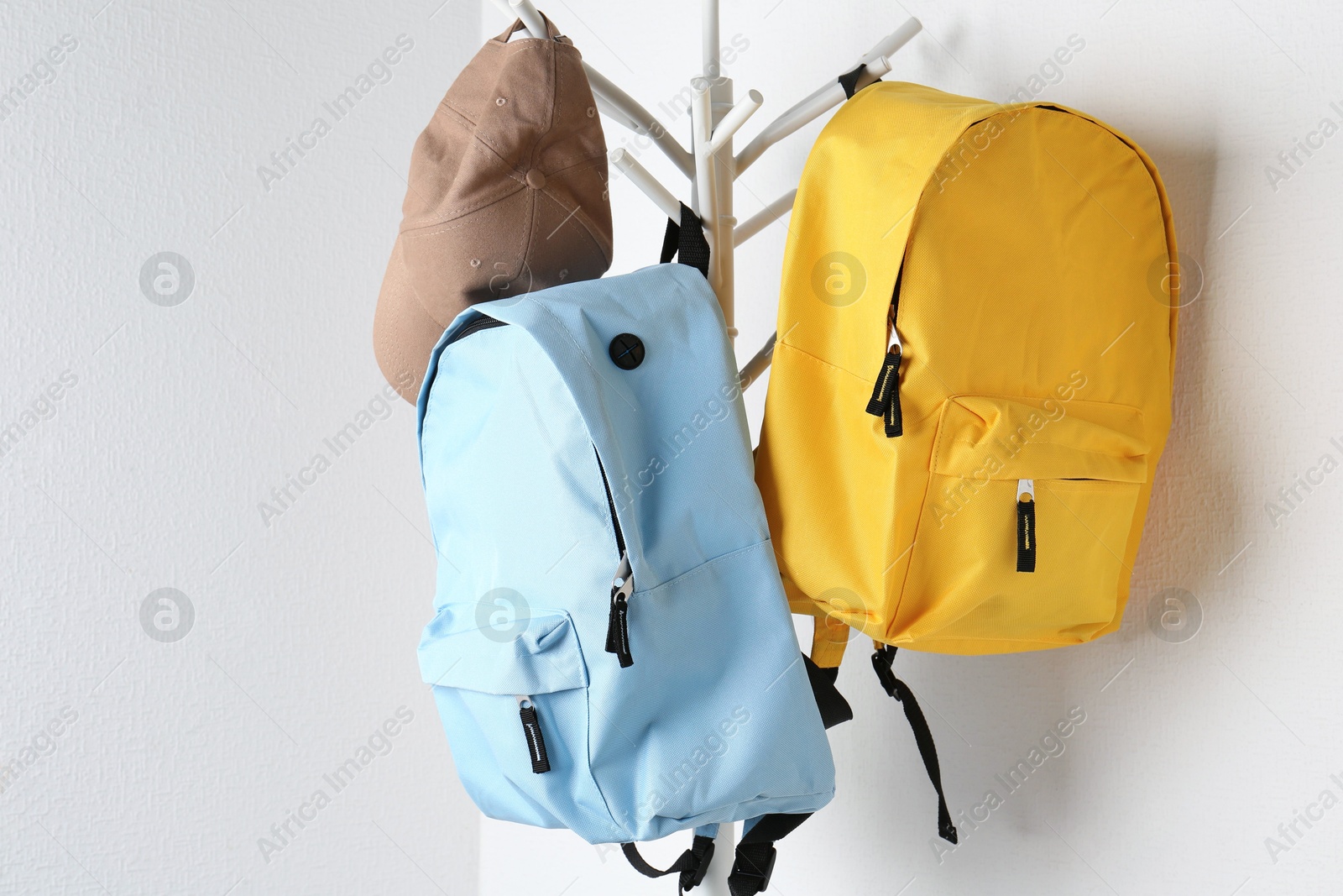 Photo of Bright backpacks and cap hanging on white wall