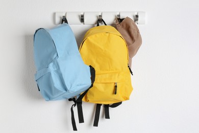 Photo of Bright backpacks and cap hanging on white wall