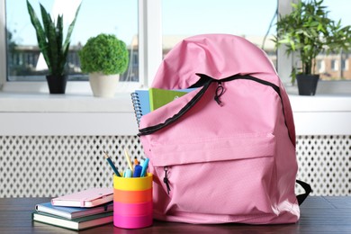 Photo of Backpack with different school stationery on wooden table indoors