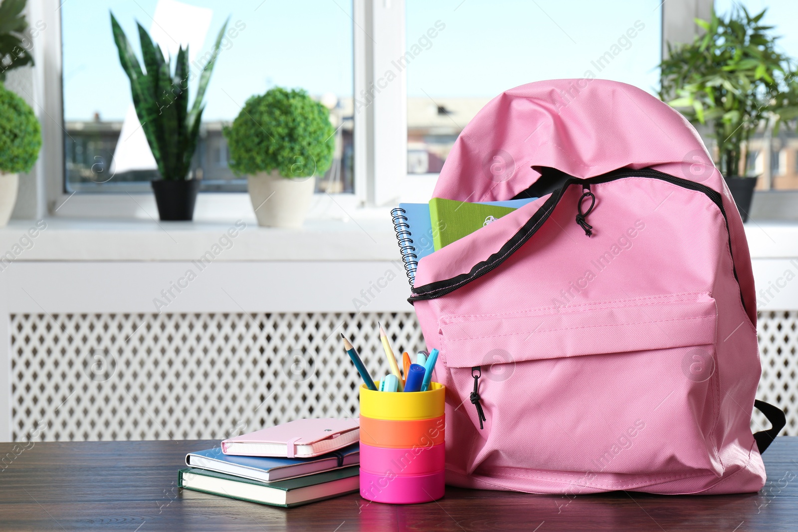 Photo of Backpack with different school stationery on wooden table indoors