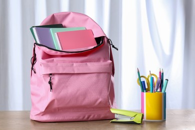 Photo of Backpack with different school stationery on wooden table